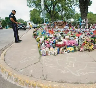  ?? ERIC GAY/AP ?? A police officer pauses Thursday during a visit to the memorial at Robb Elementary School in Uvalde, Texas, created to honor the victims killed in the recent school shooting.