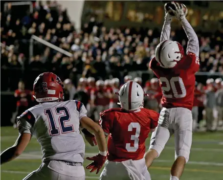  ?? STUART CAHILL / HERALD STAFF ?? CLIMB THE LADDER: Melrose’s Charles Haggerty (right) intercepts the ball in the end zone as Revere’s Dillan Day and Melrose’s Christophe­r Cusolito look on as Melrose won the Div. 4 North sectional title, 41-7.