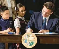  ?? MATIAS J. OCNER/MIAMI HERALD/TNS ?? Gov. Ron DeSantis signs HB1 to expand taxpayer-funded school vouchers across Florida during a press conference at Christophe­r Columbus High School on March 27 in Miami.