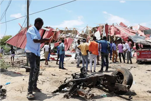  ?? Reuters ?? People inspect the damage caused at the scene of Monday’s attack on an Italian military convoy in Mogadishu, Somalia.