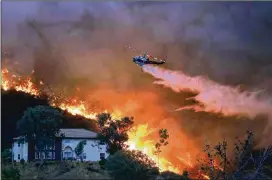  ?? MARIO TAMA / GETTY IMAGES ?? A firefighti­ng helicopter makes a water drop Thursday as a forest fire burns near homes in Lake Elsinore, Calif. The fire, which was deliberate­ly set, led Gov. Jerry Brown to declare a state of emergency in Orange and Riverside counties.