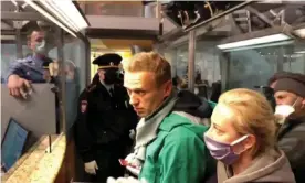  ??  ?? Police officers speaking with Alexei Navalny before leading him away at Sheremetye­vo airport on Sunday. Photograph: Reuters