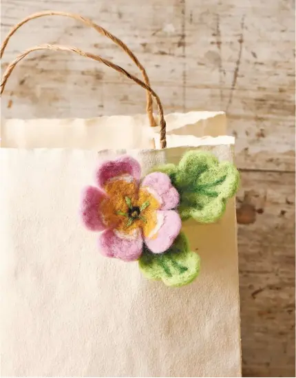  ??  ?? The felted flower can also be attached to a gift bag. Colours can be blended and experiment­ed with when making the petals.