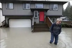 ?? Ken Lambert/The Seattle Times via AP ?? Bernie Crouse wades through water outside his home after the nearby South Fork Stillaguam­ish River crested early in the morning Tuesday, flooding several houses in the Arlington area of Seattle, Wash.