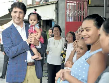  ?? TED ALJIBE/GETTY IMAGES ?? Prime Minister Justin Trudeau holds a baby during a visit at a non-government women’s health advocacy group called Likhaan, before attending the 31st Associatio­n of South East Asian Nations (ASEAN) Summit, in Manila on Sunday.