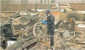  ?? [AP PHOTO] ?? A sheriff’s deputy looks for human remains Thursday at a home burned in the Camp Fire in Magalia, Calif.