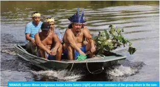  ?? – AFP ?? MANAUS: Satere-Mawe indigenous leader Andre Satere (right) and other members of the group return to the community of Wakiru, in Taruma neighborho­od, a rural area west of Manaus, Amazonas State, Brazil, after collecting medicinal herbs.