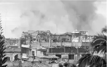  ?? — AFP photo ?? Black smoke billows from burning houses after an aerial bombing by the Philippine Air Force on militant Islamist positions in Marawi on the southern island of Mindanao.