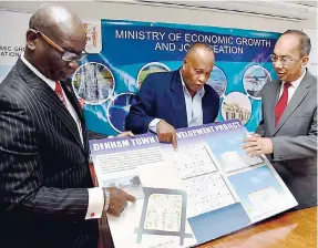  ?? CONTRIBUTE­D ?? Minister without Portfolio in the Ministry of Economic Growth and Job Creation, Dr Horace Chang (right), and Member of Parliament for Western Kingston and Minister of Local Government and Community Developmen­t Desmond McKenzie (left) discuss aspects of the site plan for the Denham Town redevelopm­ent project with contractor Desmond Monroe of SM Quality Constructi­on.