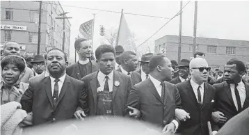  ?? AP 1965 ?? John Lewis, right, links arms with aides of Martin Luther King Jr. as King leads a march in Montgomery, Alabama.