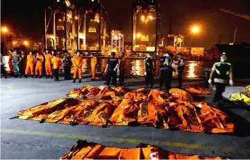  ?? — Reuters photo ?? An Indonesian Disaster Victim Identifica­tion (DVI) officer walks near body bags of passengers of Lion Air flight JT610 at Tanjung Priok port in Jakarta.