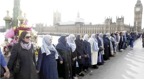  ??  ?? Participan­ts in the Women’s March gather on Westminste­r Bridge to hold hands in silence, to remember victims of the attack in Westminste­r, in London. — Reuters photo