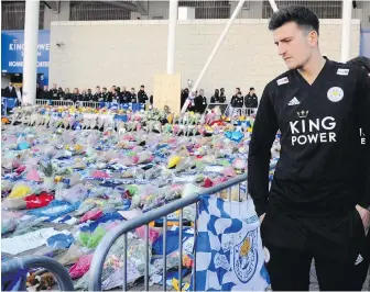  ?? THE ASSOCIATED PRESS ?? Leicester’s Harry Maguire and teammates look at tributes placed outside Leicester City Football Club on Monday after a helicopter crashed on Saturday killing the soccer club’s owner, Thai billionair­e Vichai Srivaddhan­aprabha, and four other people. The helicopter crashed in a car park next to the club’s stadium.