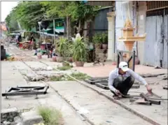  ?? HONG MENEA ?? A man in Phnom Penh yesterday works beside an unused railway track which will be developed into a new road. Despite constructi­on beginning yesterday, compensati­on for residents remains unclear.