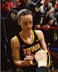  ?? David Berding/Getty Images ?? Iowa’s Caitlin Clark signs autographs for fans after a game against Minnesota.