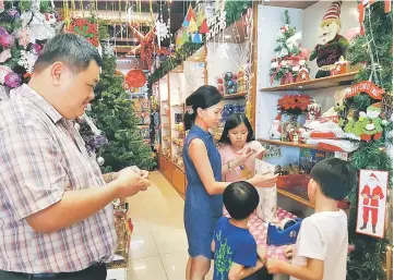  ??  ?? Jasmine (second left) packing Christmas gifts for her customers at Katai’s outlet at Jalan Padungan here yesterday.