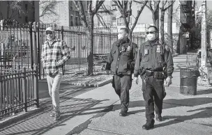  ?? DIANA ZEYNEB ALHINDAWI/NEW YORK TIMES ?? Masked police officers walk by a pedestrian in Manhattan this week.