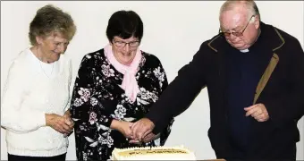  ??  ?? Angela Turner and Elizabeth Sheehan assist Fr Sheehan to cut the cake at the farewell function for the priest which was held recently in Caherdanie­l Hall.