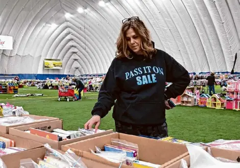  ?? Photos by Lori Van Buren/times Union ?? Event organizer Cathy Wood goes through items Thursday for the Pass It On sale happening this weekend at Afrim’s Sports Dome in Latham. Tens of thousands of items will be consigned.