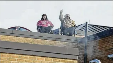  ?? KAREN SCHIELY / BEACON JOURNAL ?? Eric Jackson, the principal of Wadsworth Middle School, gives a thumbs-up to students as he and Dave Ryder, the assistant principal, settle in to camp overnight on the roof of the school Tuesday.