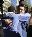  ??  ?? Krista Terrell, left, hugs her friend, Hyong Yi, before Yi and his children handed out 100 love notes along Tryon St. on Friday.