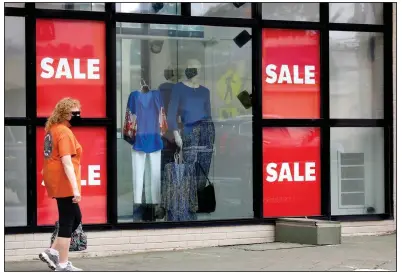  ?? (Arkansas Democrat-Gazette/John Sykes) ?? A woman walks Friday past a clothing store display window containing masked mannequins on Kavanaugh Boulevard in Little Rock’s Heights neighborho­od. Consumer spending rose in May, the Commerce Department reports.