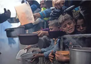  ?? FATIMA SHBAIR/AP ?? Palestinia­ns line up for a free meal Friday in Rafah, Gaza Strip. Internatio­nal aid agencies say Gaza is suffering from shortages of food, medicine and other basic supplies as a result of the war between Israel and Hamas.