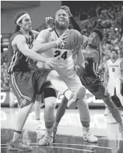  ?? WILLIAM MANCEBO/GETTY IMAGES ?? Gonzaga’s Przemek Karnowski, hounded by USF defenders Matt McCarthy, left, and Nate Renfro, dropped 23 points on the Dons as the Zags won their 27th straight game.