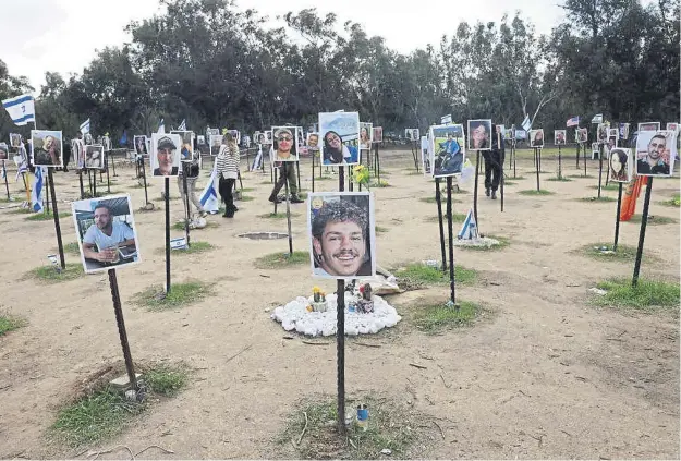  ?? ?? People walk past portraits of people taken captive or killed by Hamas militants during the October 7 attacks, during a visit at the site where the Supernova music festival took place near Kibbutz Reim in southern Israel.