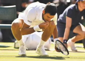  ?? Glyn Kirk / AFP / Getty Images ?? Novak Djokovic samples the grass on Centre Court, where he beat Kevin Anderson 6-2, 6-2, 7-6 (3) to win his fourth Wimbledon title. The result gave him 13 Grand Slam championsh­ips.