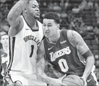  ?? Brandon Dill Associated Press ?? KYLE KUZMA drives against Memphis forward Jarell Martin during the first half. Kuzma went on a 7-0 run by himself in the fourth quarter to help lift the Lakers.