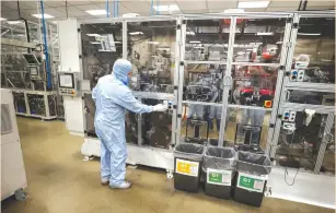  ?? (Phil Noble/Reuters) ?? A WORKER in a protective suit operates a machine inside the Envision battery manufactur­ing plant at Nissan’s Sunderland factory, earlier this month.