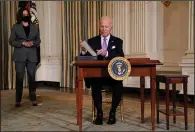  ?? (AP/Evan Vucci) ?? President Joe Biden signs executive orders Tuesday in the State Dining Room of the White House with Vice President Kamala Harris standing nearby.