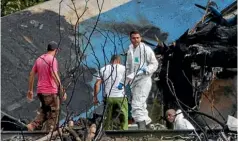  ?? AP ?? Forensic investigat­ors and Ministry of Interior officers sift through the remains of a Boeing 737 that plummeted into a yuca field with more than 100 passengers on board in Havana, Cuba.