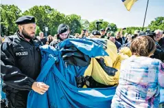  ?? ?? Police roll up a Ukrainian flag reading ‘they are us’ at the Soviet War Memorial in Berlin