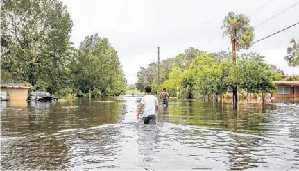  ?? AILEEN PERILLA/STAFF PHOTOGRAPH­ER ?? Angel Garavito, 15, and his friend Moses Figareau, 16, wade through water after Hurricane Irma ripped through Orange County’s Orlo Vista neighborho­od in the early-morning hours Monday. Orange firefighte­rs and members of the National Guard pulled more...