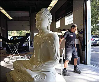  ?? JESSIE WARDARSKI / AP ?? Dave Ley, co-owner of Exoticars, an auto restoratio­n shop specializi­ng in classic vehicles, pulls a restored statue of the Buddha outside in McCandless, Pa. on Oct. 11. Workers repaired and repainted the figure for the Pittsburgh Buddhist Center, which brought it from Sri Lanka over 15 years ago.