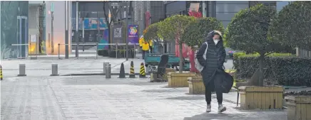  ?? PHOTO / AP ?? A face-masked woman walks through a deserted street. Universiti­es are sending students home as the ruling Communist Party tightens anti-virus controls and tries to stop more student protests.