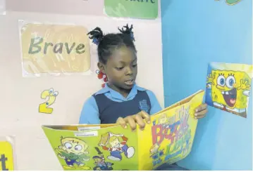  ?? ?? Nine-year-old Mcintosh Memorial Primary student Rickelicia Ellis reading a book inside the Manchester Parish Library on Wednesday.