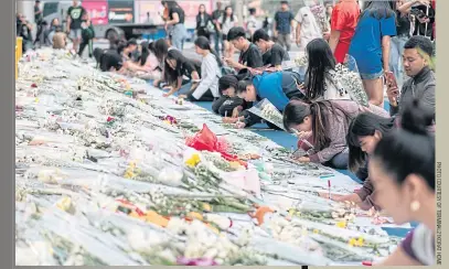  ??  ?? People lay flowers and write condolence messages in front of Terminal 21 in Nakhon Ratchasima, in memory of those who lost their lives in the shooting.