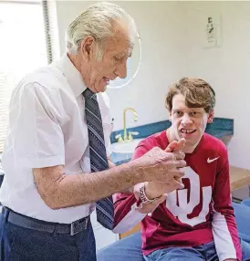  ?? [PHOTOS BY CHRIS LANDSBERGE­R, THE OKLAHOMAN] ?? Retired chiropract­or Anthony Guadagno, 86, shows Parker Swinney hand exercises while they visit at Oklahaven Children’s Chiropract­ic Center.