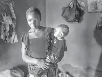  ?? JEROME DELAY/AP ?? Anayo Mbah, 29, holds one of her children in her home in Umuida, Nigeria, on Feb. 11. Mbah delivered her sixth child the same day she learned her husband died of COVID-19. His family stopped supporting her and sent her away weeks later.