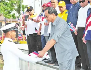  ??  ?? SERAH:Jaujan (kanan) menyempurn­akan acara penyerahan Jalur Gemilang ketika di majlis berkenaan.