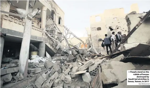  ?? Hani Mohammed ?? > People stand on the rubble of houses destroyed by Saudi-led airstrikes in Sanaa, Yemen, in 2017