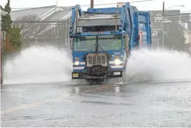  ?? THOMAS P. COSTELLO/ASBURY PARK PRESS ?? A garbage truck plows through high water along East Main Street in Manasquan on Dec. 18. Heavy rain falls are increasing at “levels significan­tly above historic trends, placing inland properties at greater risk of flash flooding,” according to new research.
