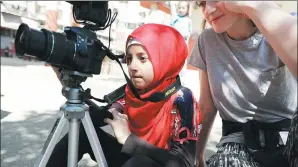  ?? JOSEPH EID / AGENCE FRANCE-PRESSE ?? Tahani al-Shaalan, a 9-year-old Syrian refugee, films her friends as they perform in Shatila as part of a program called the Refugee Film Project, an initiative that teaches children how to write, direct and act in their own movies.