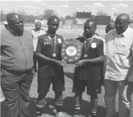  ??  ?? Hwange captains Obert Moyo (left ) and Gerald Ndlovu pose with the championsh­ip shield flanked by Zifa Southern Region chairman Andrew Tapela (right) and board member Fiso Siziba.