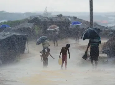  ?? (AFP) ?? A Rohingya child carries water during rain in a refugee camp in Bangladesh’s Ukhia district on Thursday