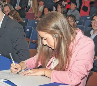  ??  ?? Antonella, de 23 años, firmando su flamante título en la entrega de Diplomas.