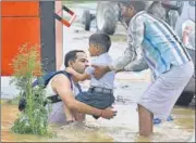  ?? SANJEEV VERMA/HT PHOTO ?? A father who braved the rain to carry his son to school through the flooded roads had a narrow escape when the man lost his balance and almost fell after the road level changed drasticall­y. The man was chestdeep in water when passersby caught his son and helped him regain balance.